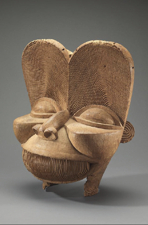 wooden carved tribal mask with large ears and detailed textured surface in brown