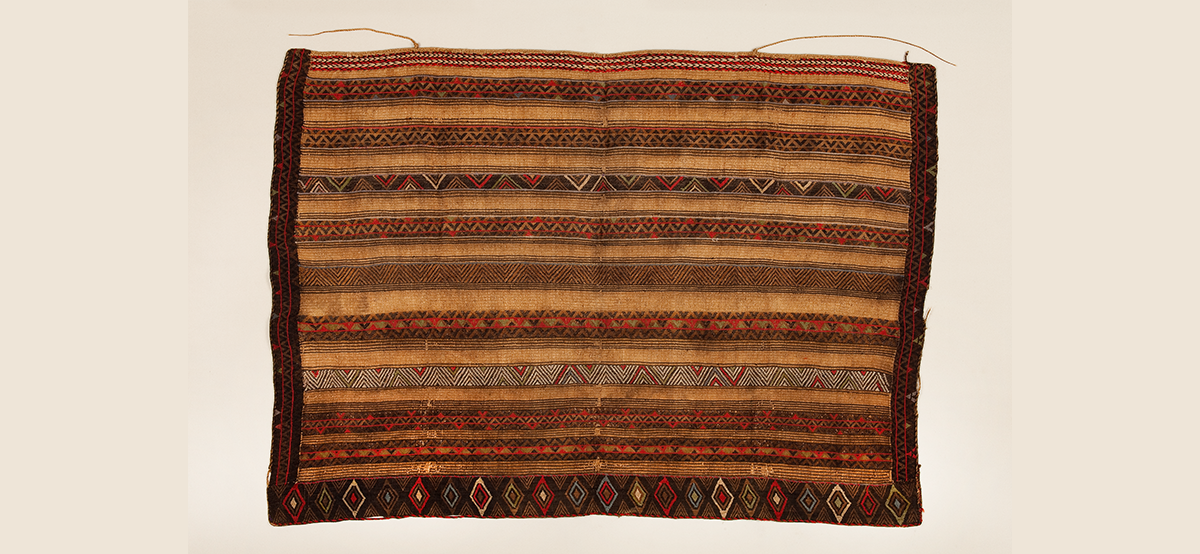 Rectangular woven textile with geometric patterns made of natural fibers in brown, red, and black colors