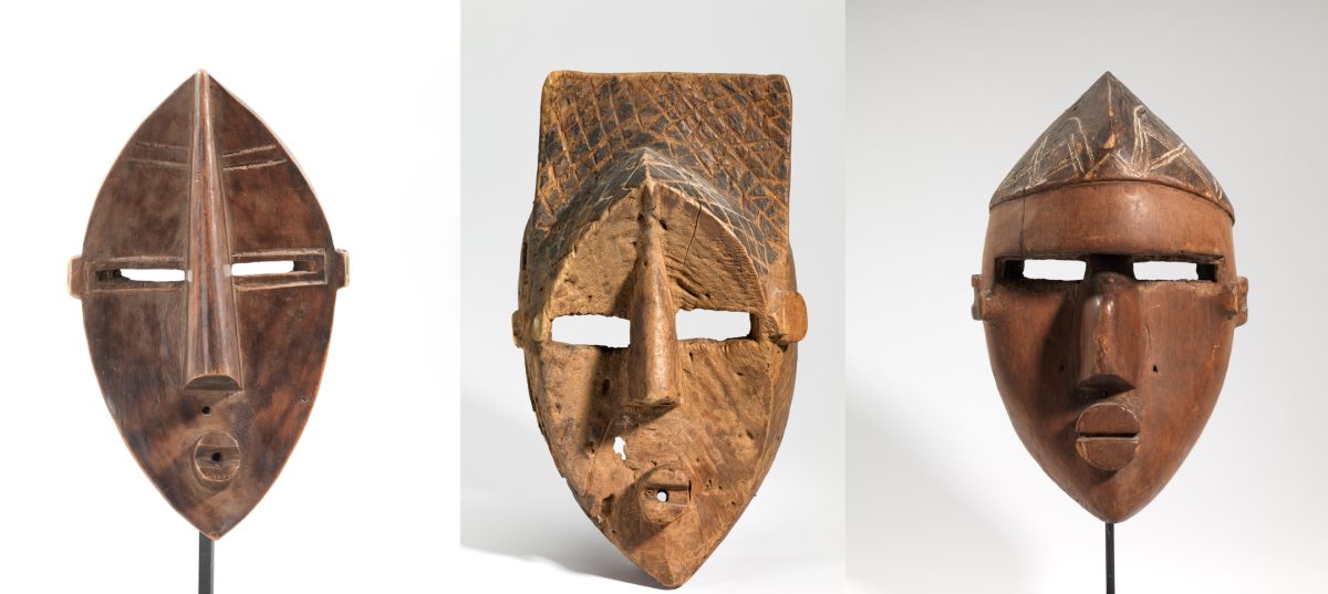 Three wooden tribal masks with carved geometric patterns in brown and tan shades